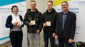 Prof. Dr. Andreas Riener (rechts), zwei der Gewinner (mitte), Martina Schuß (links) bei der Übergabe der Gutscheine. Quelle: THI