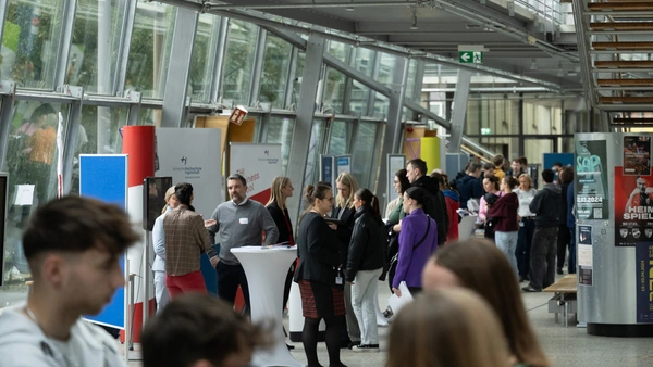 Ein Blick auf die verschiedenen Info-Stände der Fakultäten mit vielen Besuchern, darunter auch die Business School.