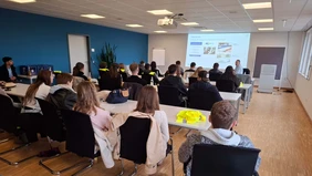 A full meeting room - a presentation is shown at the front. 