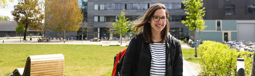 Eine Studentin steht auf dem Campus vor einem THI-Gebäude